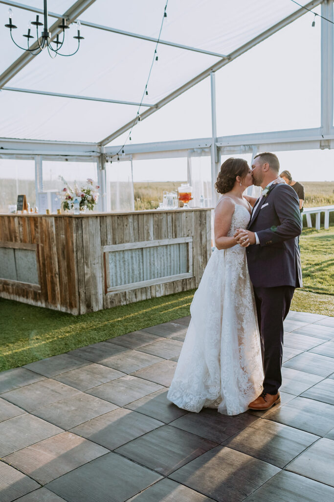 A couple sharing a kiss on a dance floor at an outdoor wedding venue.