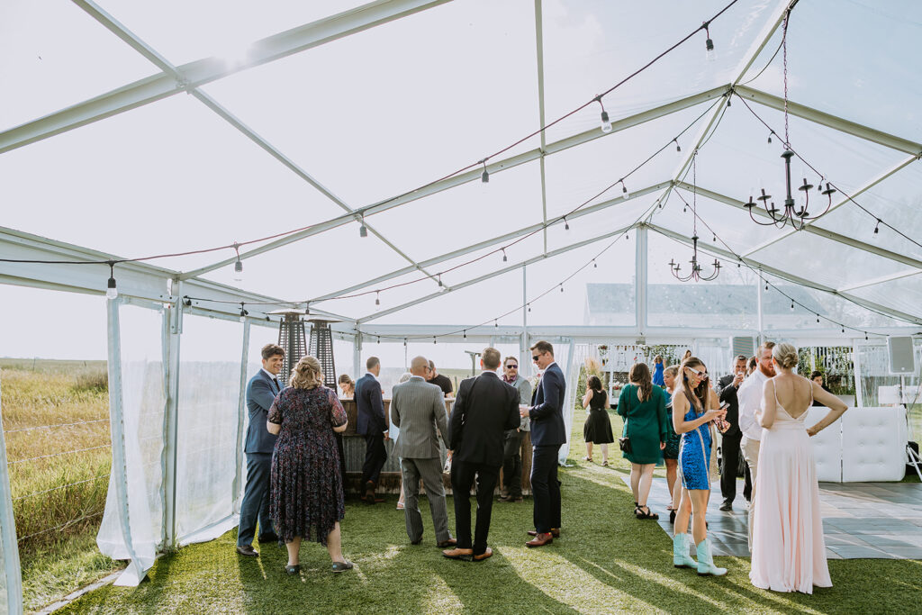 Guests mingling under a tent at an outdoor event.