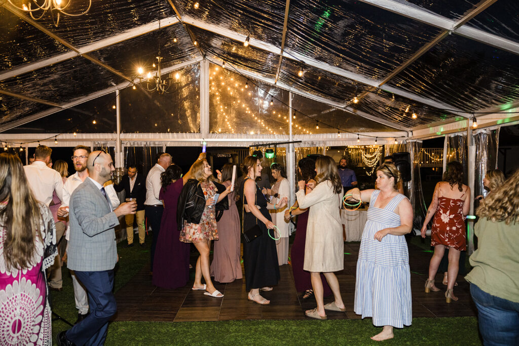 An evening outdoor gathering under a tent with string lights, where guests are socializing.