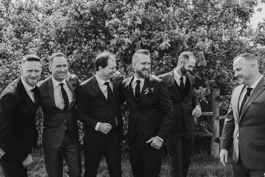 Group of men in suits laughing together outdoors.