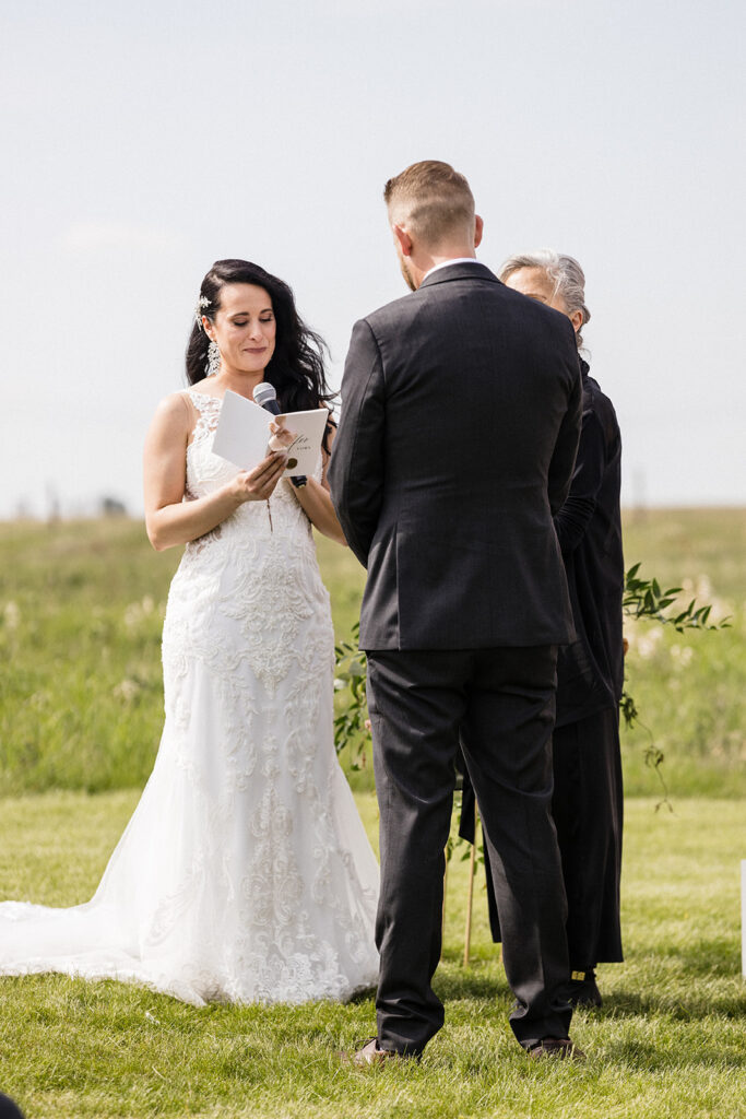 Bride reading her vows to the groom during an outdoor wedding ceremony.