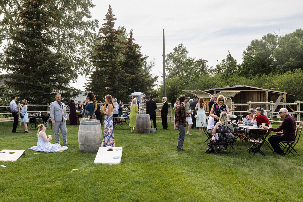 Guests socializing at an outdoor event with some seated at tables and others standing on the grass.