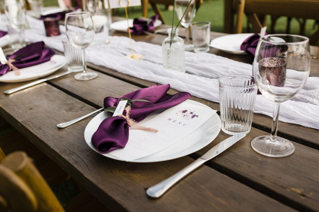 Elegant outdoor table setting with a purple napkin and a menu for a formal event.