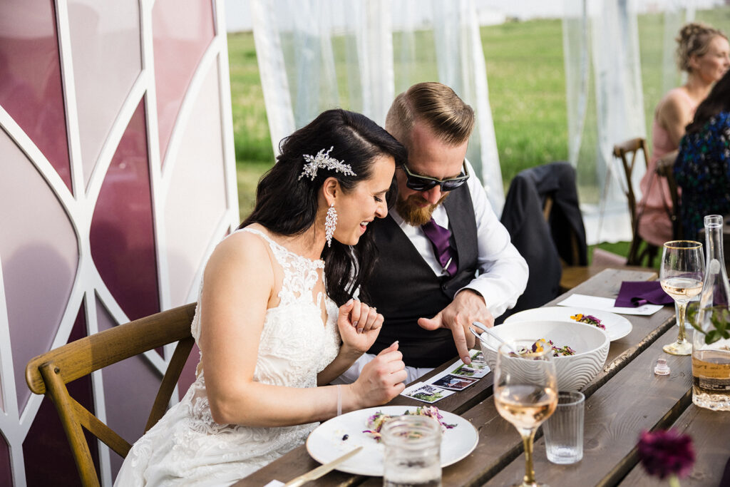 Bride and groom looking at photographs at their wedding reception table.