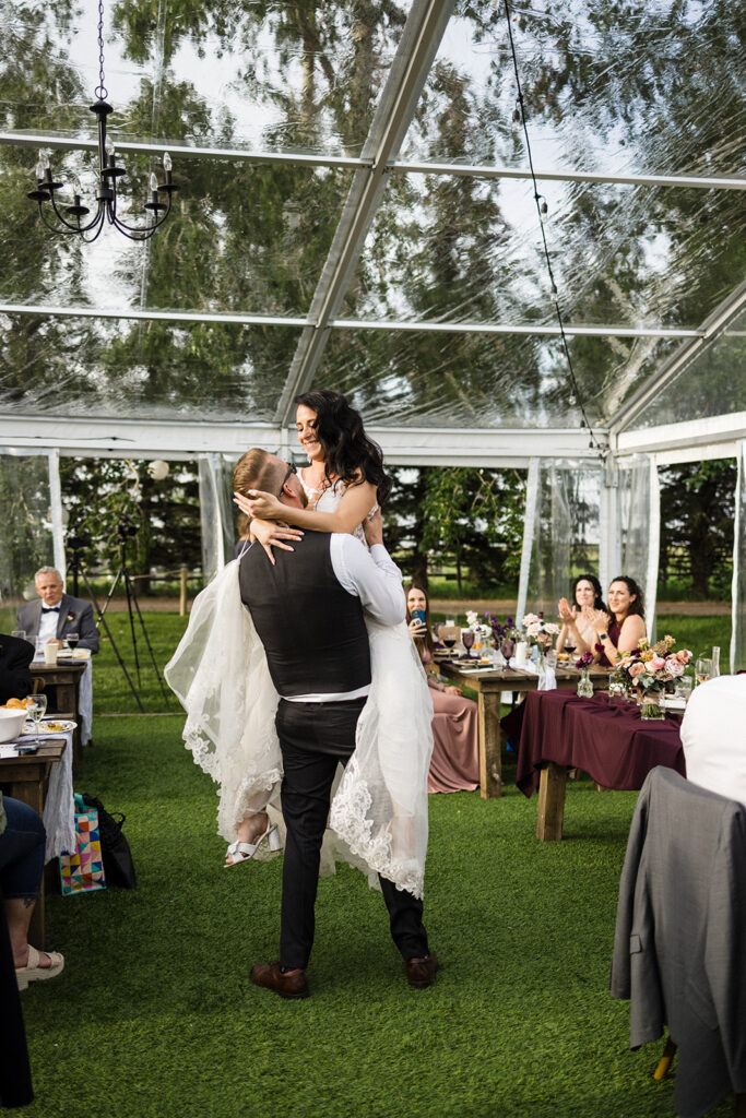 Bride and groom share a dance under a tent at an outdoor wedding reception.