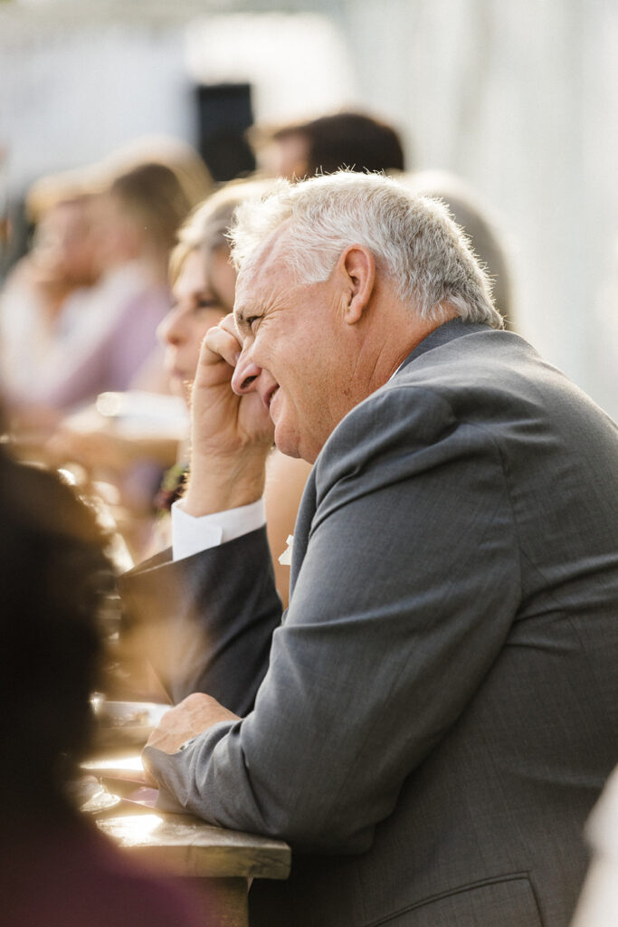An elderly man sitting and watching attentively at a social event.