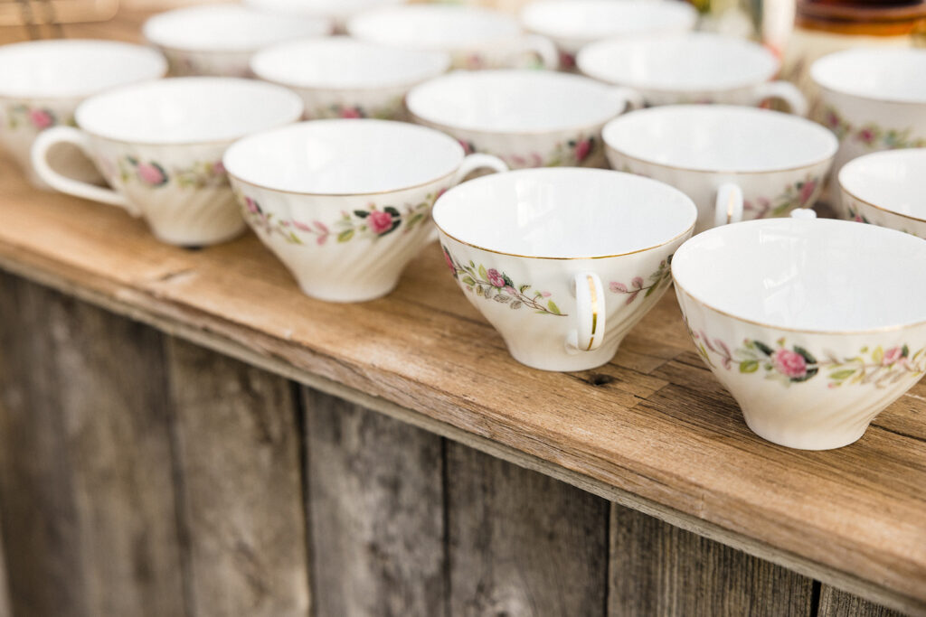 Row of vintage teacups with floral design arranged on a wooden surface.