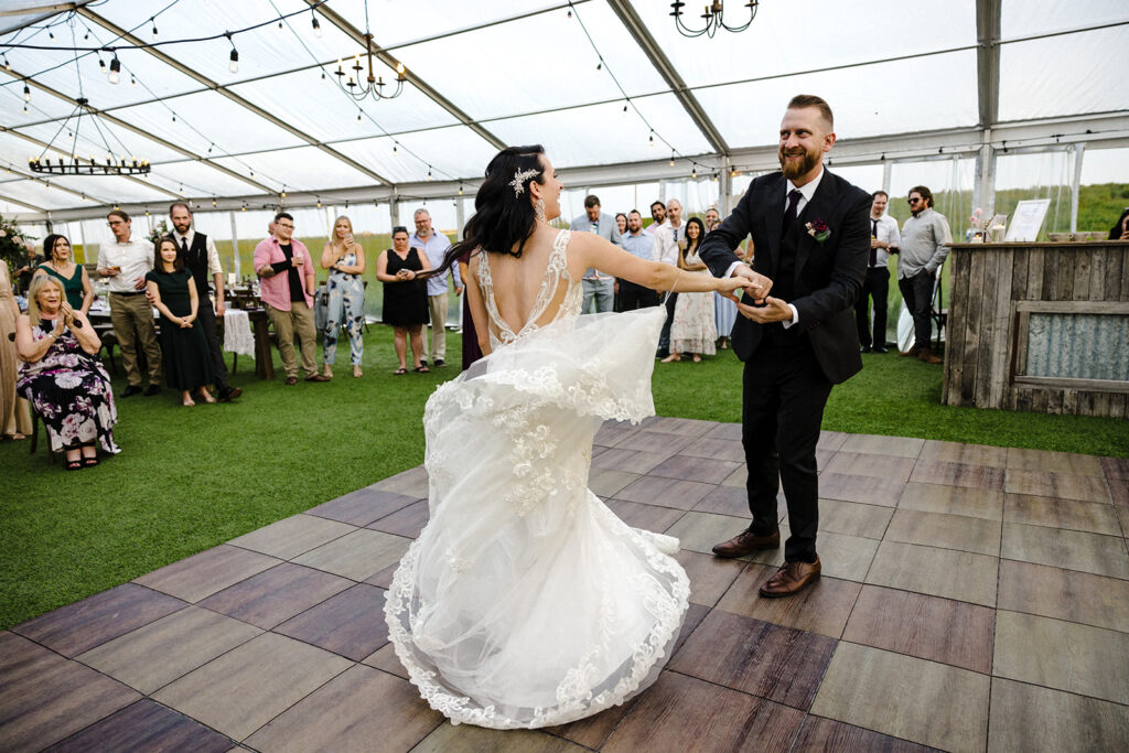 Bride and groom enjoying their first dance outdoors with guests watching.