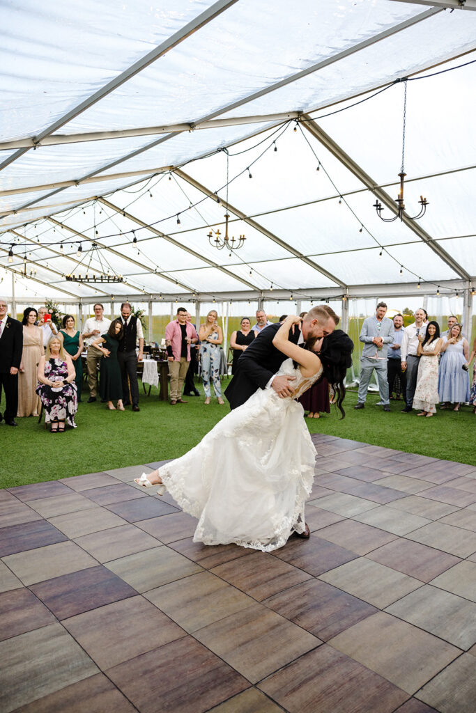 Bride and groom sharing their first dance under a tent at a wedding reception.