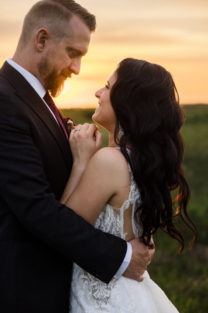 A couple in formal wear sharing an intimate moment at sunset.