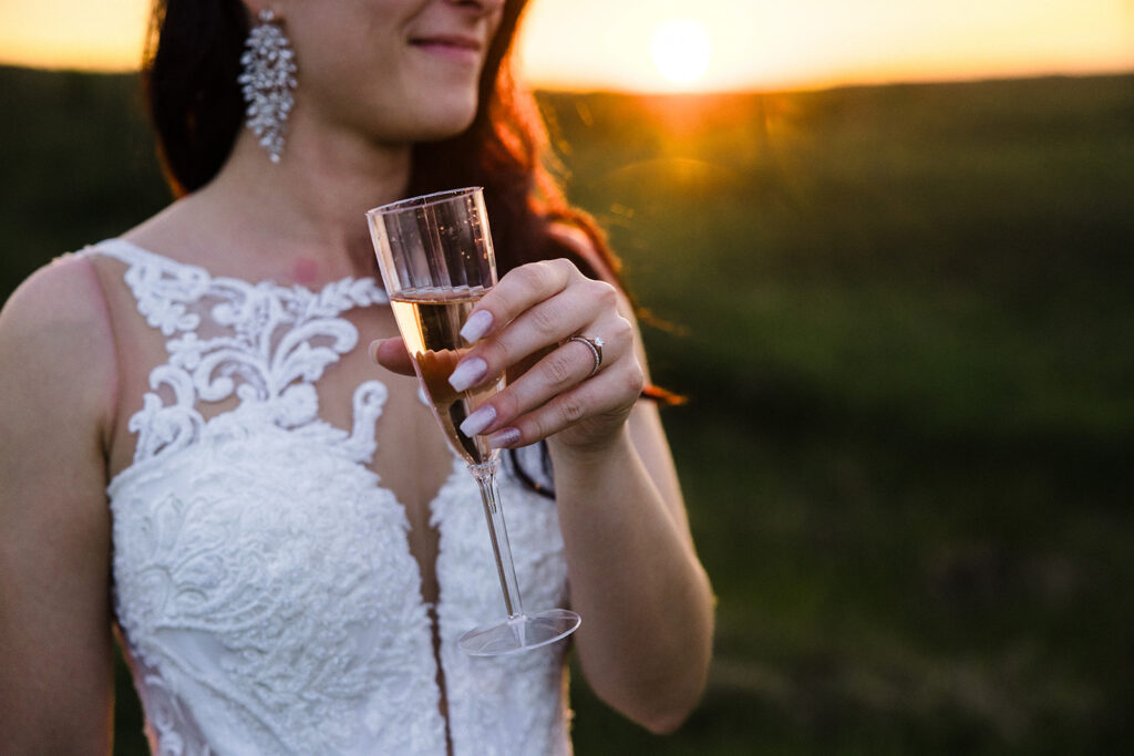 Bride holding a champagne glass at sunset.