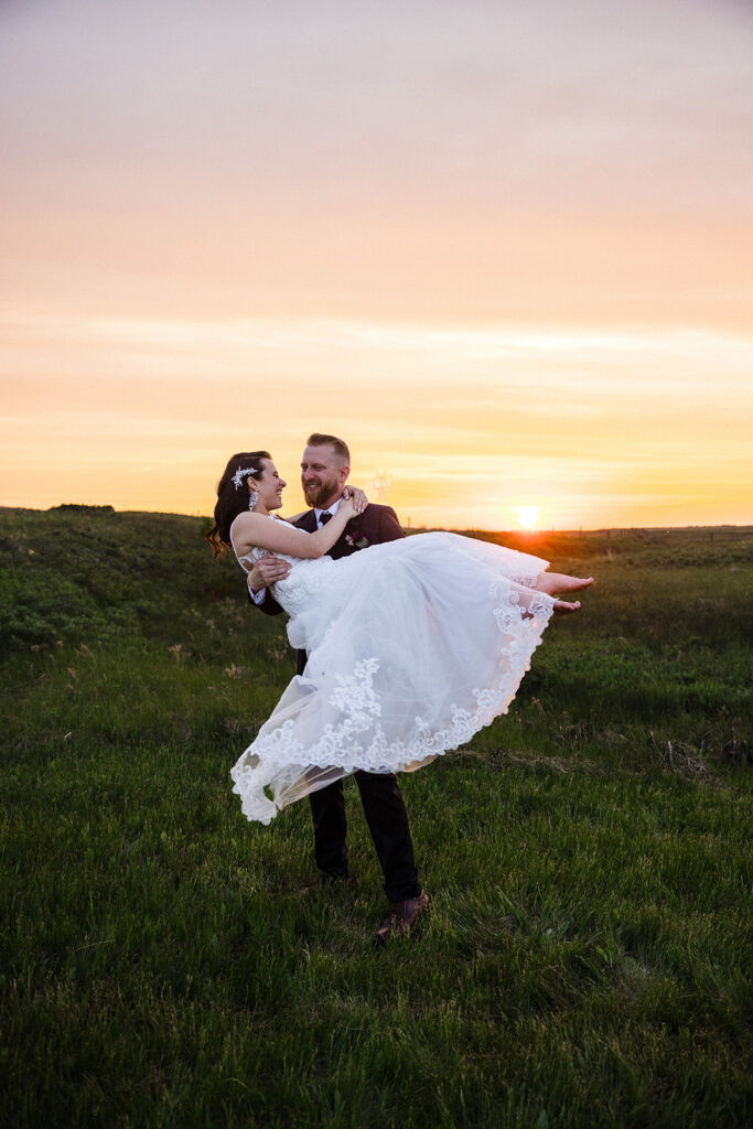 A joyful couple dancing in a field at sunset.