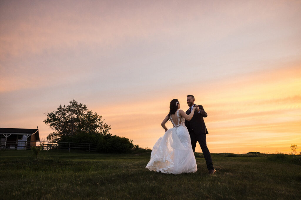 A bride and groom sharing a moment during sunset with a scenic sky in the background.